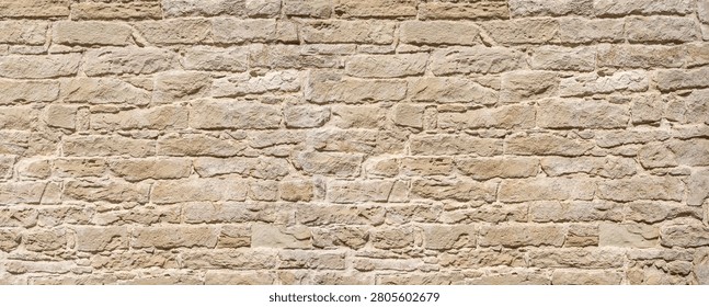 Old stone wall built with irregular blocks presenting a rough texture and weathered surface