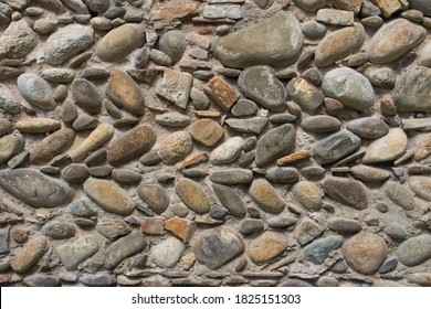 Old stone wall. Wall of medieval house. Antique architecture details. Decorative design of ancient building facade. Granite and pebbles in the wall. Stones concept wallpaper. 