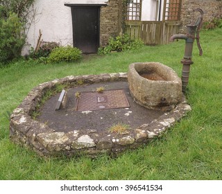 Old Stone Water Trough Below A Hand Operated Water Pump On The Green In The Rural Village Of Iddersley In Devon, England, UK