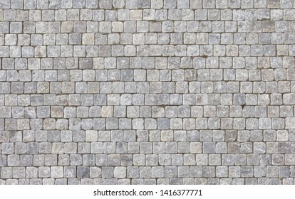 An old stoneblock pavement cobbled with square granite blocks. 