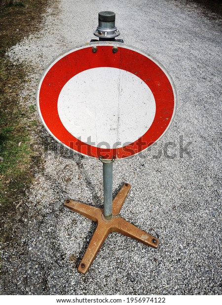 An old\
stop sign on a metal stand on a gravel\
path.