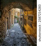 Old street with arch in Bussana Vecchia. Ghost town in Sanremo, Liguria region, Italy. Abandoned due to an earthquake in 1887, today is a community of artists.