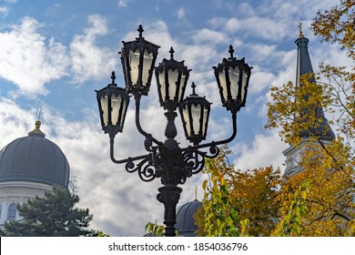 Old street lamp in front of the cathedral on a clear autumn day, against the background of a cloudy sky