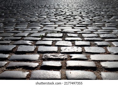 an old street made of textured cobblestones in a ray of sunlight