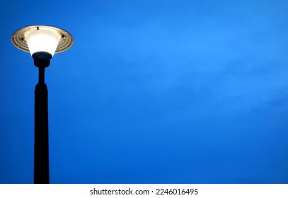 Old streetlight on blue sky with delicate clouds at sunset