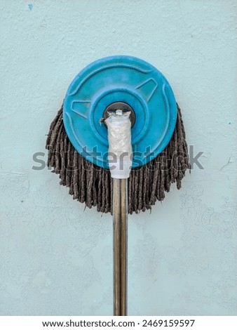 Old string mop resting against a wall