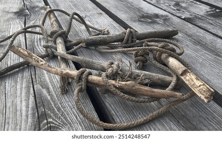 an old sturdy rope rope lies on an ancient wooden floor made of gray planks, an old marina for mooring a ship and access to the port, a convenient cable for parking boats of yacht boats - Powered by Shutterstock