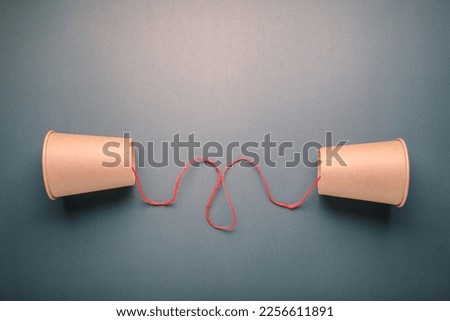 Old style cup phone with red string at the center, concept for two way communication, information transmission, sender and receiver, communicate with each other