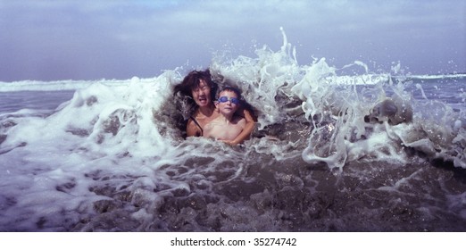 Old Style Image Shot On Film Of Mother And Son Hit By Ocean Wave