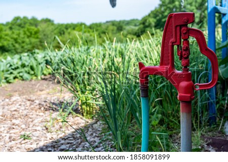 Old style mechanical self draining hydrant in blurred rural garden setting