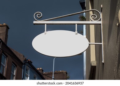 Old Style Oval Metal Sign Board Hanging On A Wall In A Street. White Color And Empty Space For Message. Retro Style Advertisement Theme