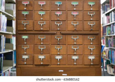 An old style wooden cabinet of library card  or file catalog index drawers with label holders and blank labels facing front, database concept.