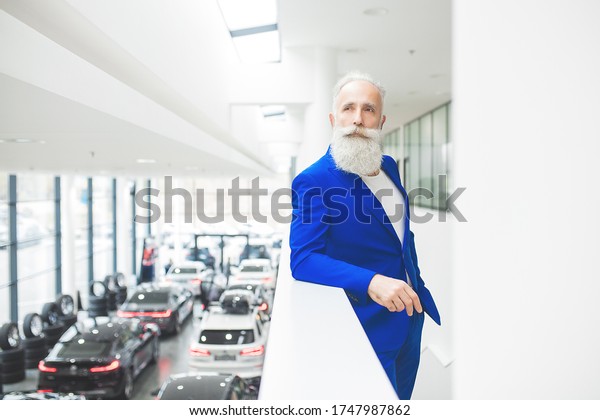 Old stylish man in car sales center. Mature\
man choosing new\
automobile.