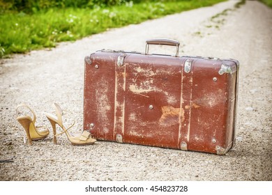 Old suitcase and high heel sandals on the rural road