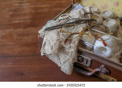 Old Suitcase With Vintage Napkin, Scissors, Glasses And Sewing Thread