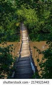 Old Suspension Bridge Over The River In The Countryside Going Into Perspective.