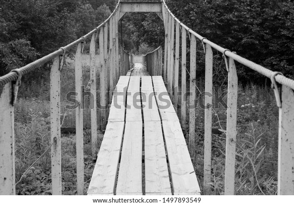 old suspension bridge over a small river\
in the forest in summer, bridge\
elements