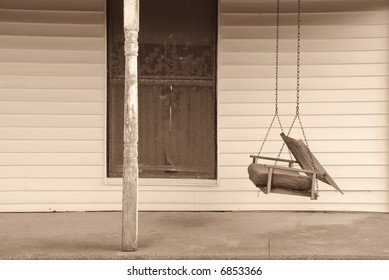 An Old Swing On The Front Porch Of An Abandoned House.