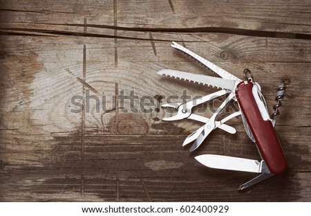 old Swiss knife on a wooden background. Top view with copy space