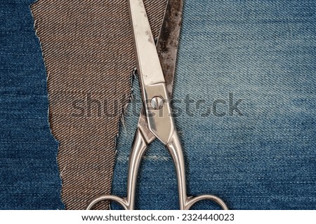 Old tailor scissors on blue jeans background.Upcycle old denim garbage. Recycling old jeans. 
