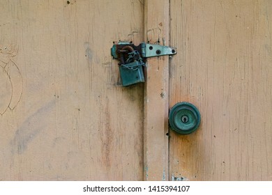 An Old Tarnished Brass Pad Lock And Door Knob That's On A Wooden Door.