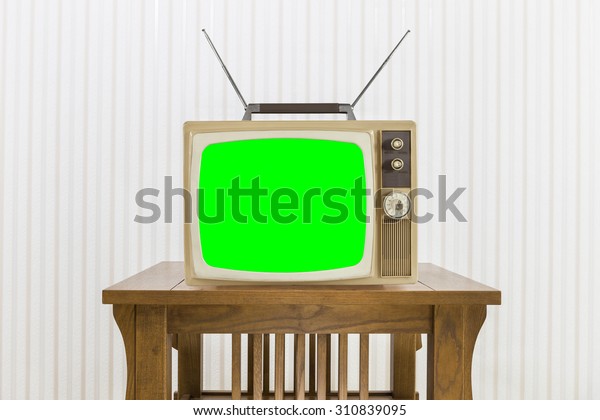 Old television with antenna on wood table with\
chroma screen.