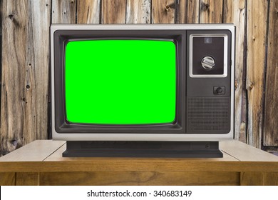 Old television with chroma key green screen and rustic wood wall.