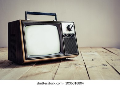 Old Television On Wooden Table With Concrete Wall Background, Vintage TV Technology With Filter Effect