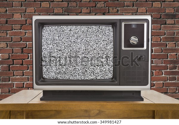 Old\
television with static screen and brick\
wall.