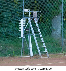 Old Tennis Umpire Chair On A Red Tennis Court