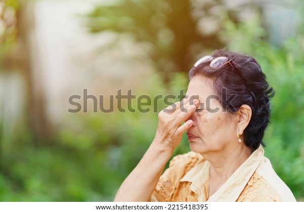 An\
old Thai woman wears glasses on her head to massage her eye sockets\
because she has pain in her eyes. Health care\
concept.