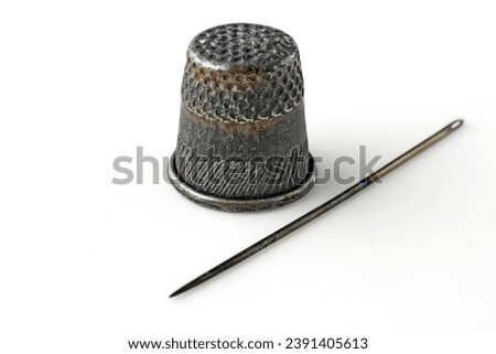 Old thimble and rusty sewing needle isolated on white background.