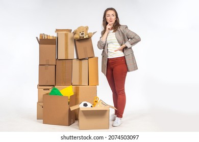 Old things in boxes. Concept - unnecessary personal items in woman's boxes. She thinks about storage space. Woman with boxes on light background. She needs place for personal storage