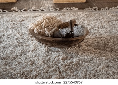 Old threads and spinning tools are placed in a wooden bowl on a white carpet