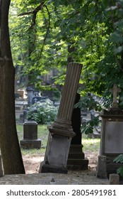 Old tilted column monument stands on a grave inside a cemetery yard. Historical churchyard tombstone represents decay, passing of time, funeral mourning and graveyard heritage conservation.
