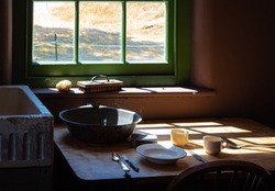 Old Times Farmhouse Interior In A Kitchen. Rustic Farmhouse Kitchen. Rural Home Kitchen With Worn Wooden Table And Mixing Bowl, Spoon, Plate. Selective Focus, Nobody, Concept Photo Old Times Life
