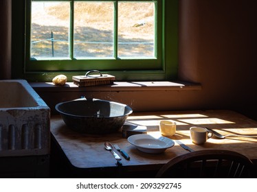 Old times farmhouse interior in a kitchen. Rustic Farmhouse Kitchen. Rural home kitchen with worn wooden table and mixing bowl, spoon, plate. Selective focus, nobody, concept photo old times life