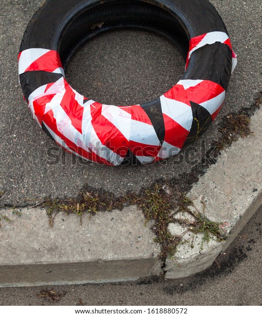 Old tire cover (wheel)\
wrapped in red and white safety strip. Self-made attention and\
danger signal.