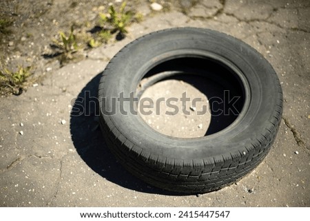 Old tire. One wheel on road. Old rubber thrown on street. Item from car. Round object.