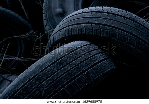 Old tires dumped in a field. Industrial\
waste / rubbish background. UK rural\
crime.