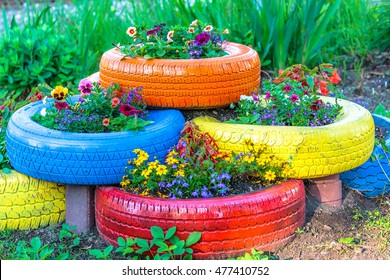 Old tires that are painted in assorted colors and used for a flower planter.