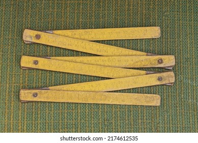 An Old Tool From One Yellow Wooden Folding Ruler Lies On A Green Table