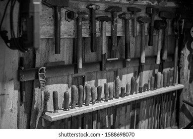 Old tools - hammers and files of different sizes on a wooden wall, black and white photo.