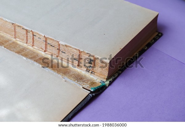 An old torn book in\
close-up. Open book flyleaf hardcover books. Paper book repair\
concept. Selective focus.