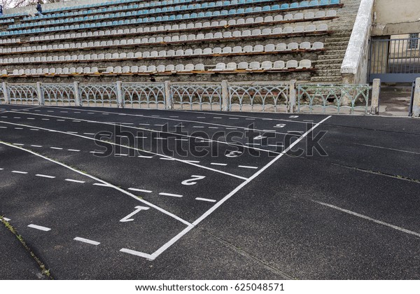 old torn\
running track. An old racing track of an abandoned ruined stadium.\
Sports dividing bands for competitions on old bitumen treadmill.\
Old track running ruined\
stadium