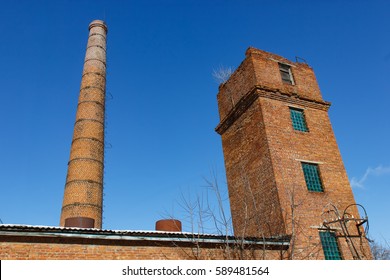 Old tower and pipe production on the background of blue sky.