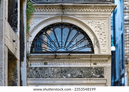 Old town of City of Venice with close-up of semi circle window with wrought iron decoration on a blue cloudy summer day. Photo taken August 6th, 2023, Venice, Italy.