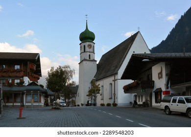 An old town hall with a church in a small German town near a mountain with hotels and restaurants - Powered by Shutterstock