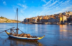 Old Town Of Porto, Portugal. Antique Boat With Port Wine Barrels On The Water Douro River. Sunny Day Over Silhouettes Skyline Roofs Houses Along River.