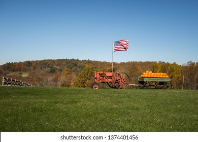 Old tractor pulling a wagon full of pumpkins, while flying The American Flag. Near Meadows of Dan.